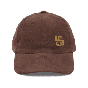 Front view of a brown vintage corduroy cap with LEDA embroidered logo. Back view of a brown vintage corduroy cap with adjustable strap and brass buckle.